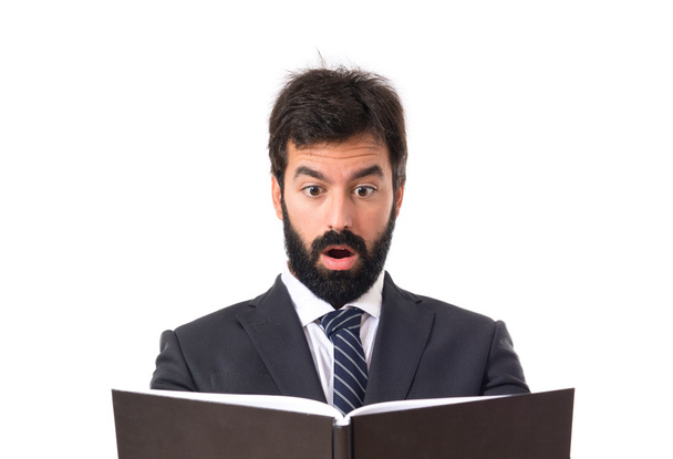 Uomo d'affari sorpreso di leggere un libro su sfondo bianco
 - Foto, immagini