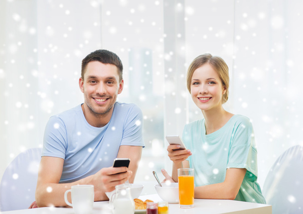 smiling couple with smartphones having breakfast - Фото, изображение