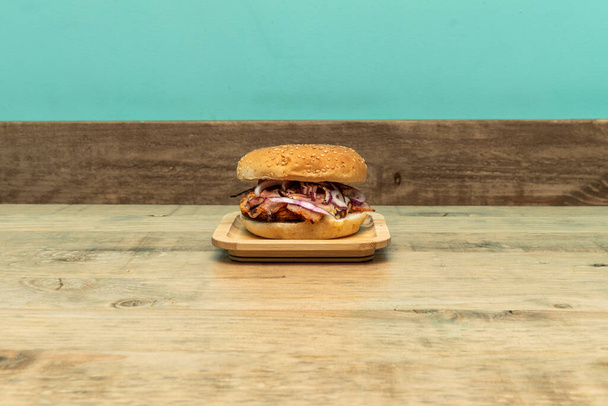Hamburger con carne alla griglia e cipolla rossa cruda sul tavolo di legno - Foto, immagini