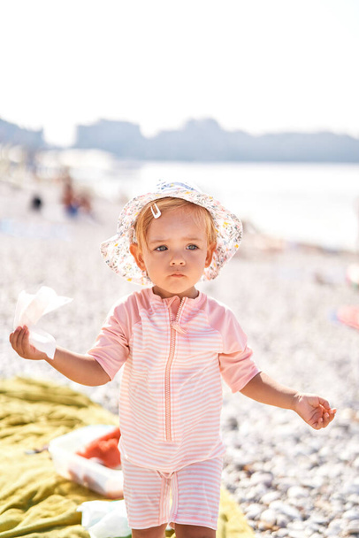 Little girl in a panama hat with a napkin in her hand on the beach. High quality photo - Fotoğraf, Görsel
