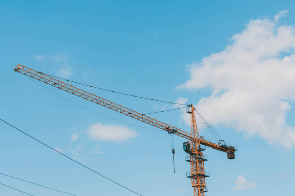 Yellow construction tower crane against blue sky.House under construction. Industrial skyline - Foto, imagen
