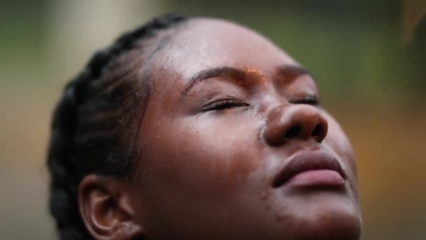 African woman face feeling the rain outside, black girl eyes closed raining droplets - Filmati, video