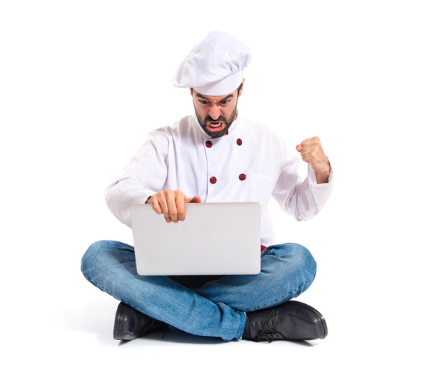 Angry chef with laptop over isolated white background - Zdjęcie, obraz