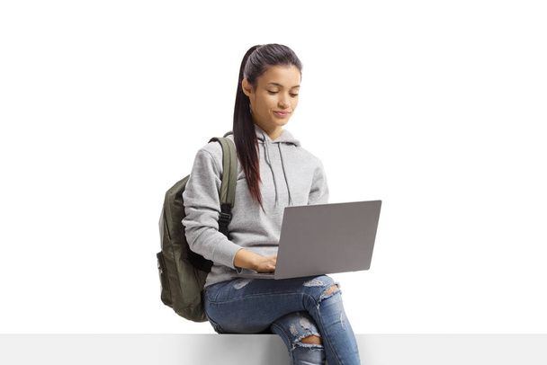 Female student sitting and using a laptop computer isolated on white background - Foto, Bild