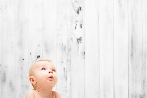 Bébé regardant vers le haut sur fond en bois blanc
 - Photo, image