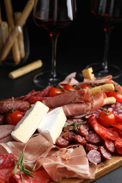 Tasty prosciutto with other delicacies served on black table - Foto, Imagem