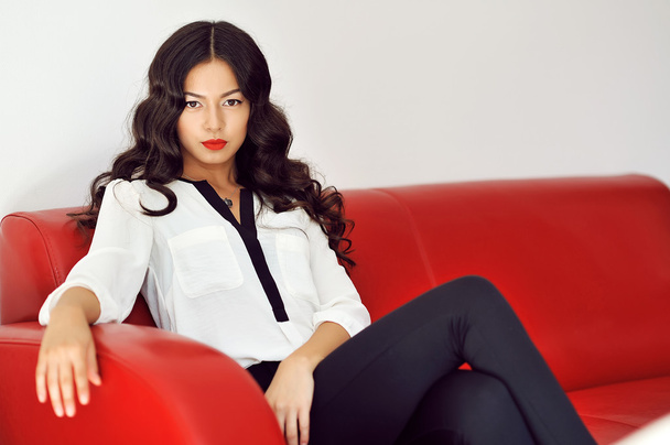 Fashion girl sitting on a red sofa at home  - Photo, Image