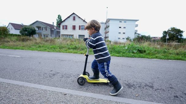 Child rides toy scooter outside - Fotó, kép