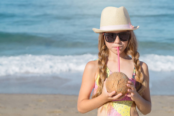 Portrait of a cute girl with a coconut and a straw on a Turkish beach. - Foto, imagen