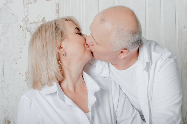 husband and wife in white shirts hug and kiss - Fotó, kép