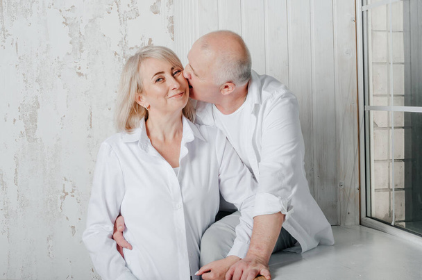 husband and wife in white shirts hug and kiss - Photo, Image