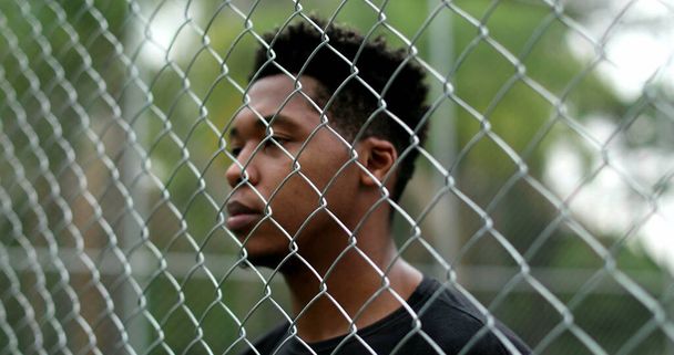 African mixed race man standing behind metal fence - Foto, Bild