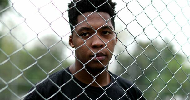 African mixed race man standing behind metal fence - Fotoğraf, Görsel