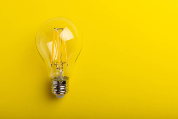 電球がついてる。エネルギー効率の概念です。黄色の背景に構図。経済的で環境に優しい電球の概念を使用する. - 写真・画像