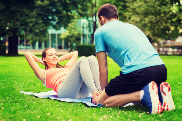 smiling woman doing exercises on mat outdoors - Фото, изображение