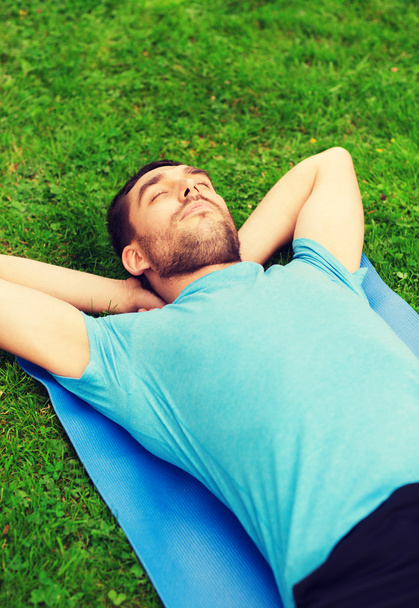 smiling man lying on mat outdoors - Foto, imagen