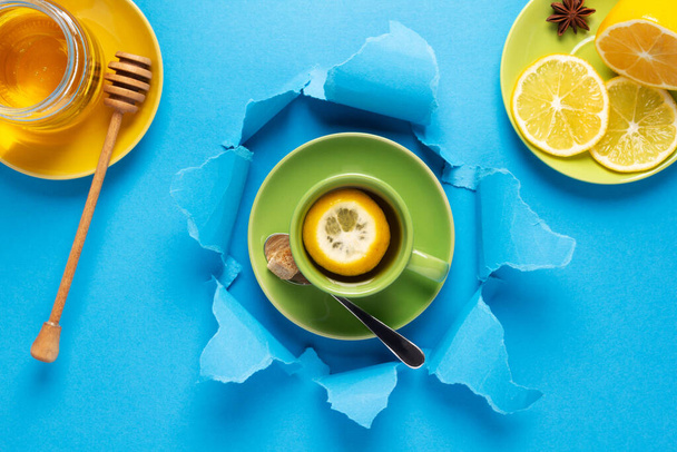 Cup of tea with lemon and honey in torn paper. Mug full of tea - Valokuva, kuva