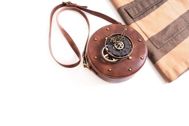 Dress and a steampunk style leather circle bag with rivets and a clock mechanism isolated on white background with copy space. - Fotó, kép