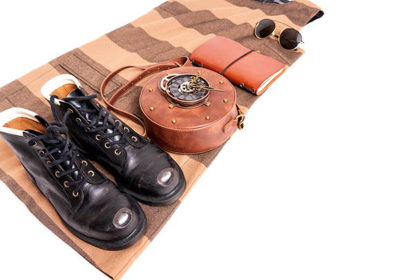 Clothes and accessories flat lay: circle clockwork leather bag, vintage work boots, journal, sunglasses, dress isolated on white. - Fotó, kép