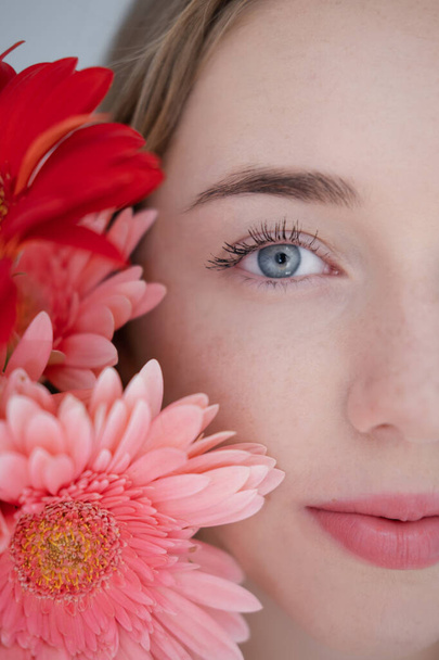 Portret van mooie jonge vrouw met roze en rode chrysant bloemen. - Foto, afbeelding