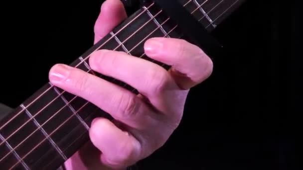 Muž hraje na kytaru. Fingers of a musician on the fretboard of a guitar close-up - Záběry, video