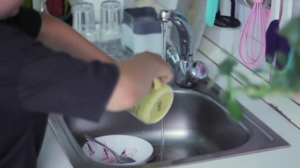 Mann spült nach dem Essen Geschirr unter fließendem warmen Wasser in der Küche - Filmmaterial, Video