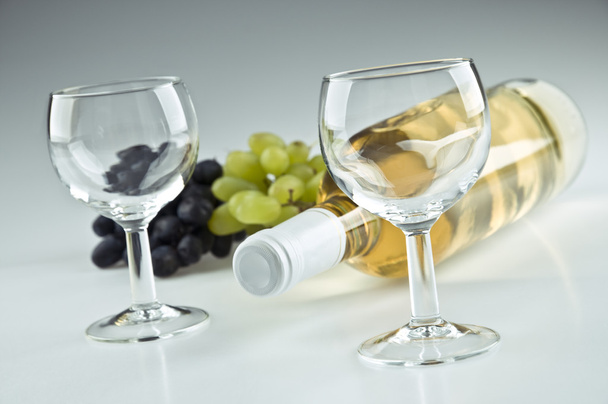 Bottiglia di bianco, due bicchieri vuoti e uva
 - Foto, immagini