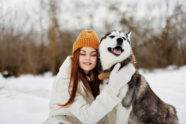 Karda mutlu genç bir kadın köpek arkadaşlığı kış tatili eğlencesiyle oynuyor. Yüksek kalite fotoğraf - Fotoğraf, Görsel