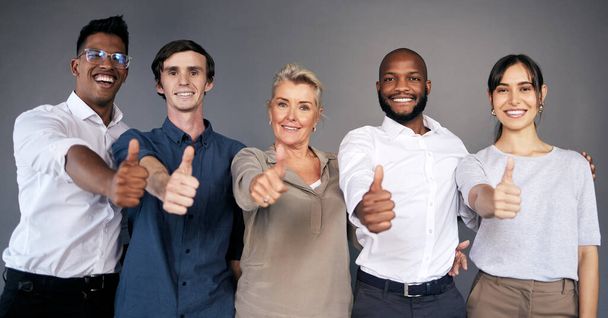 Teamwork begins by building trust. a group of workers showing a thumbs up in a office - Foto, afbeelding