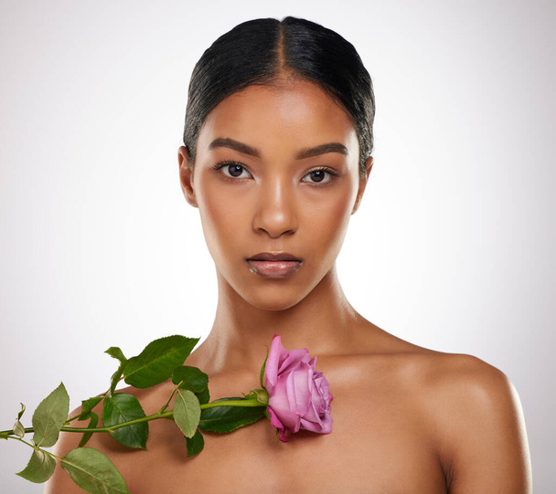 Embrace your femininity. Studio portrait of an attractive young woman posing with a pink rose against a grey background - Foto, immagini