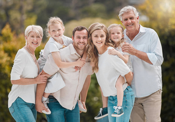 Muotokuva hymyilevä monen sukupolven valkoihoinen perhe seisoo lähellä toisiaan puutarhassa kotona. Onnellinen ihana tytöt liimaus äitinsä, isänsä, isoisänsä ja isoäitinsä kanssa takapihalla. - Valokuva, kuva
