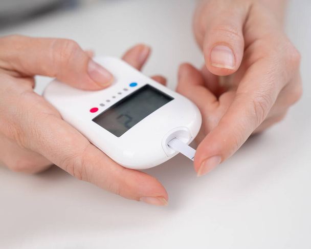 Woman measures blood sugar level with a glucometer - Zdjęcie, obraz