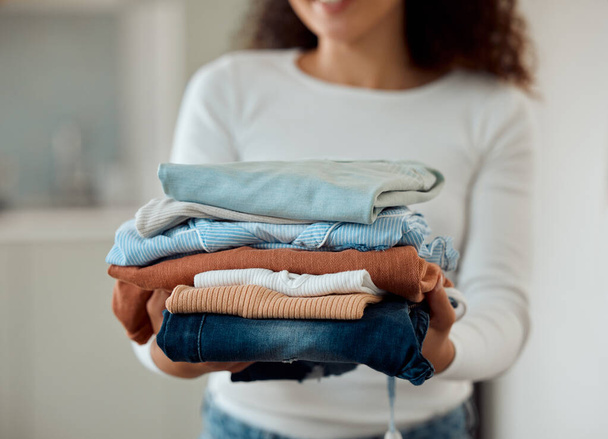 Woman cleaning a pile of laundry. Woman holding a stack of neat, folded clothing. Hands of a woman doing housework chores. Hispanic woman holding fresh, washed clothing and bedding - Photo, image
