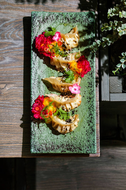 Dumpling con chuka, carne, semillas de sésamo en un plato de piedra de pie sobre la mesa - Foto, Imagen