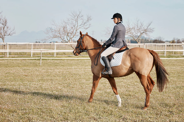 Het is een geweldige hobby. full length shot van een jonge vrouwelijke jockey rijden haar paard buiten op de ranch - Foto, afbeelding