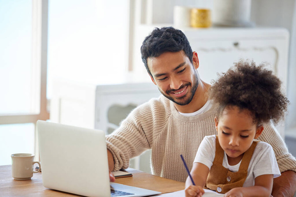 Father helping daughter with homework. Dad working on laptop, daughter drawing a sketch on paper. Man working from home on laptop. Hispanic little girl writing schoolwork on paper. - 写真・画像