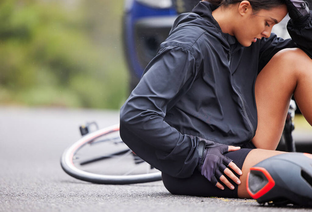 Beautiful, athletic, mixed race young woman suffering with injury while exercising outside. Healthy and sporty female athlete experiencing muscle cramps while doing a cardio workout outside in nature. - Photo, image