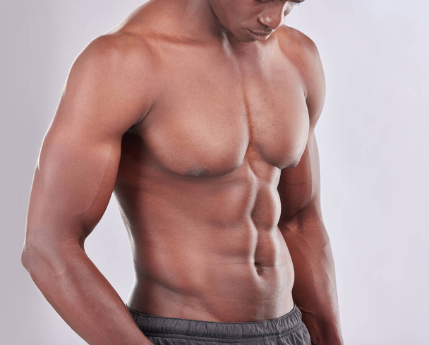 Ye, theyre rock hard. Studio shot of a muscular young man posing against a grey background - Фото, зображення