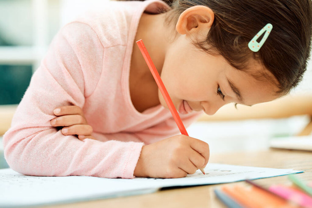 Getting down to school work. an adorable little girl doing her homework - Fotoğraf, Görsel
