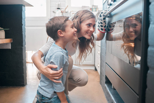 Most recently, I learned another hobby baking. a little boy and his mother sitting in front of the oven - Foto, afbeelding