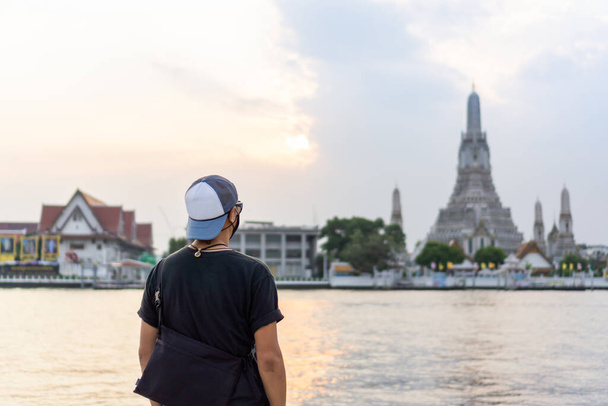 Asian male tourists with view of Wat Arun at sunset, Buddhist temple landmarks in Bangkok, Thailand. - Foto, Imagem