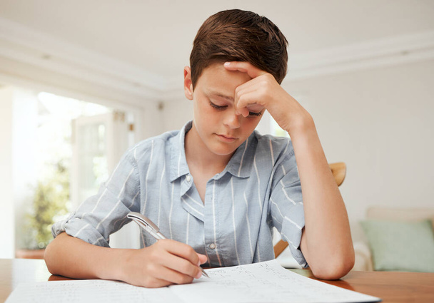Felling blue. a young boy doing his homework at the kitchen table at home - Foto, Imagen