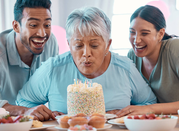 two young adults celebrating a birthday with a mature woman at home. - Foto, Imagen