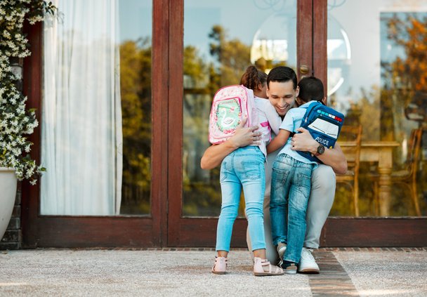 Children returning from school and hugging father on their return. Daddy missed little daughter and son holding children in arms hugging girl and boy while standing by the door. - Zdjęcie, obraz