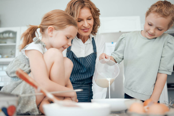 Ja nyt kaadamme maitoa. isoäiti leipoo kahden lapsenlapsensa kanssa kotona - Valokuva, kuva