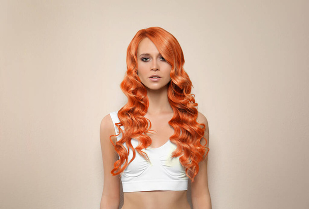 Beautiful woman with long orange hair on beige background - Foto, Bild