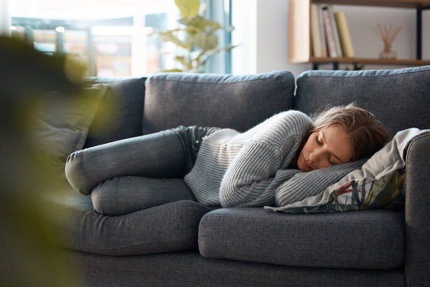 egy fiatal nő fekszik a kanapéján depressziósnak érzi magát. - Fotó, kép