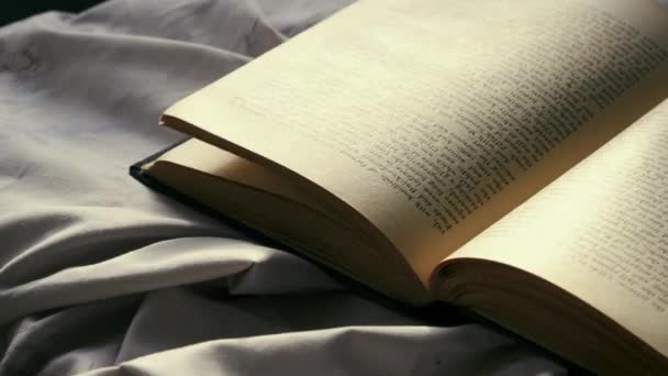Blättern Sie die Seiten eines Buches aus nächster Nähe. Eine Person blättert durch die Seiten eines alten Jahrgangs-Buches mit gedrucktem Text, der an dem Tag auf der Oberfläche liegt - Filmmaterial, Video