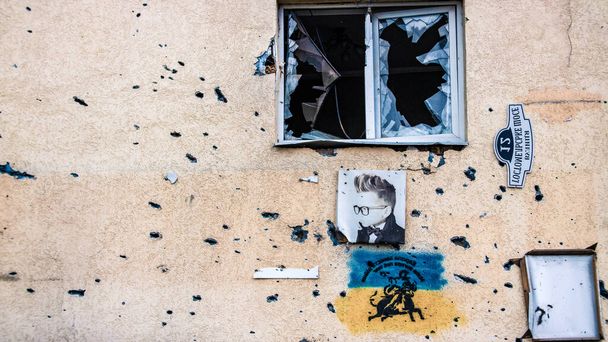 Irpin, Ukraine - May 22, 2022: a portrait of a child on the wall of a residential building, which is damaged by fragments of an exploded shell. High quality photo. - Foto, afbeelding