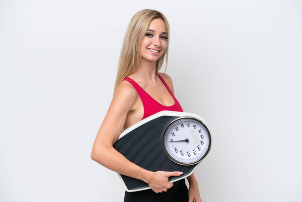 Pretty blonde woman isolated on white background with weighing machine - Φωτογραφία, εικόνα